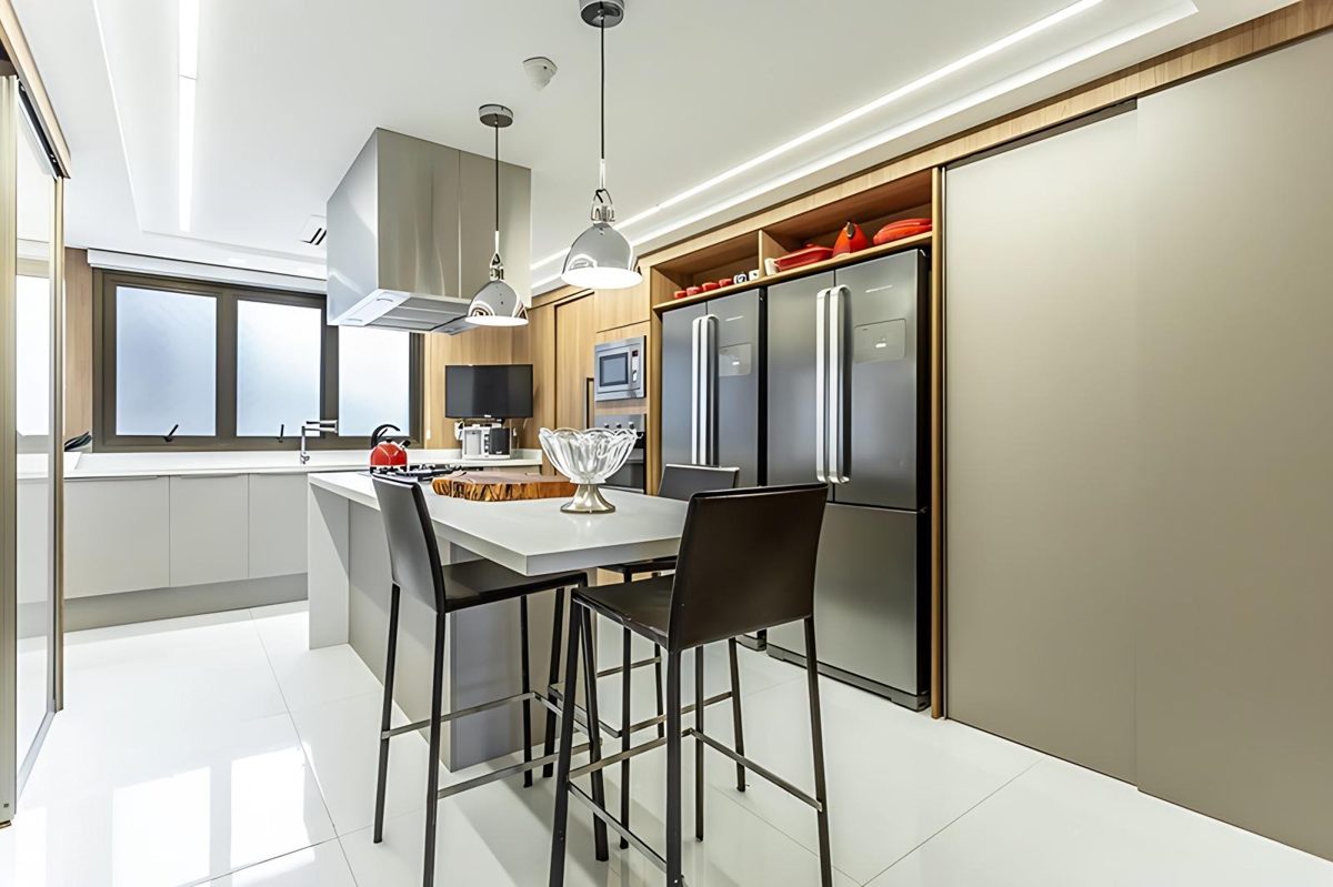 Cozinha integrada com ilha, banquetas e marcenaria em madeira, em apartamento no bairro Petrópolis, em Porto Alegre