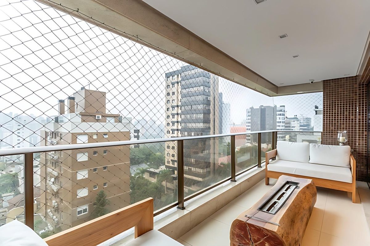 Sacada ampla com sofá e mesa de fogo, com vista para o bairro Petrópolis, em Porto Alegre
