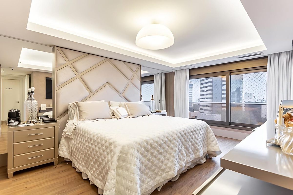 Suíte com cabeceira estofada e iluminação indireta, em apartamento no bairro Petrópolis, em Porto Alegre